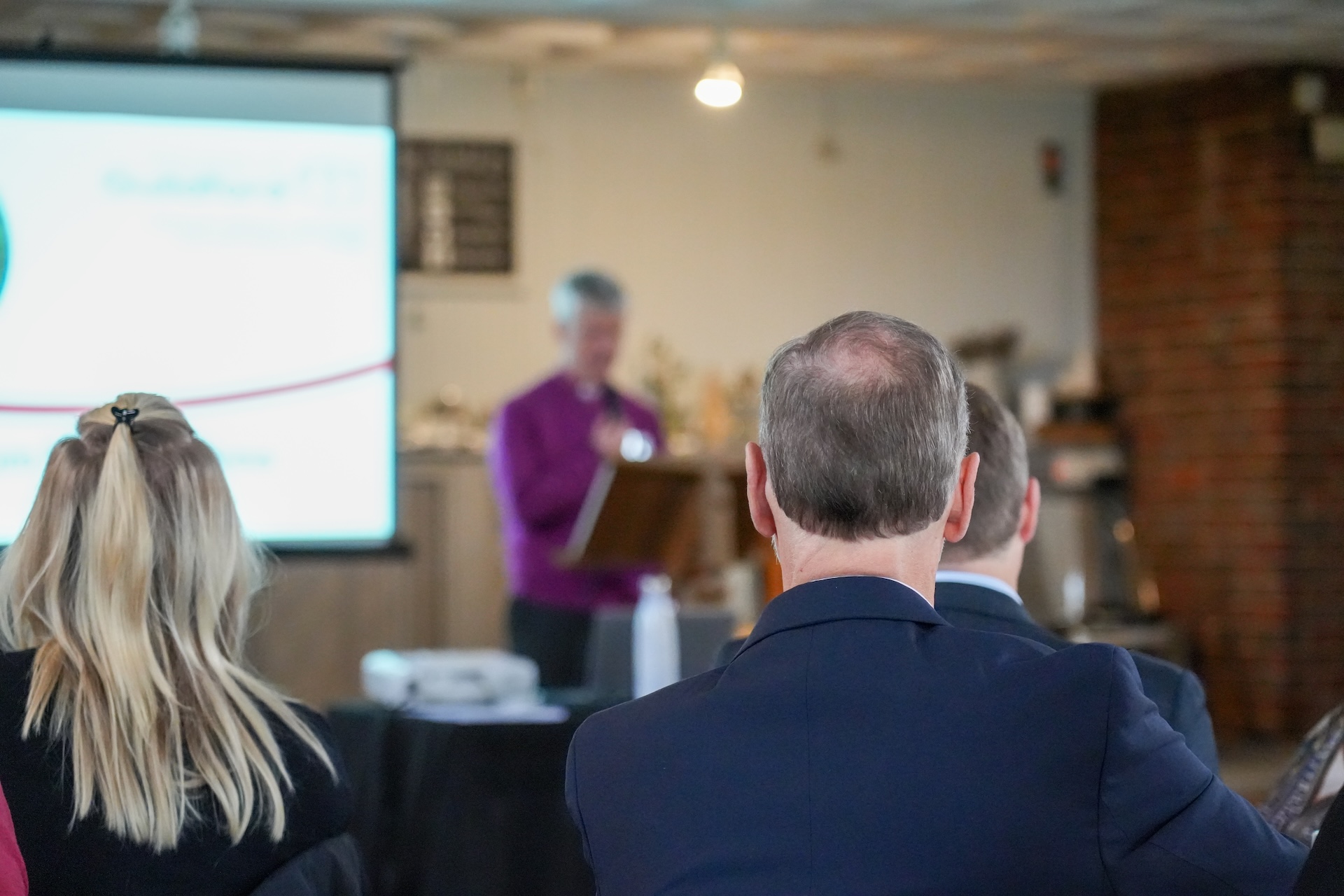 Man and woman sat watching someone presenting from a screen
