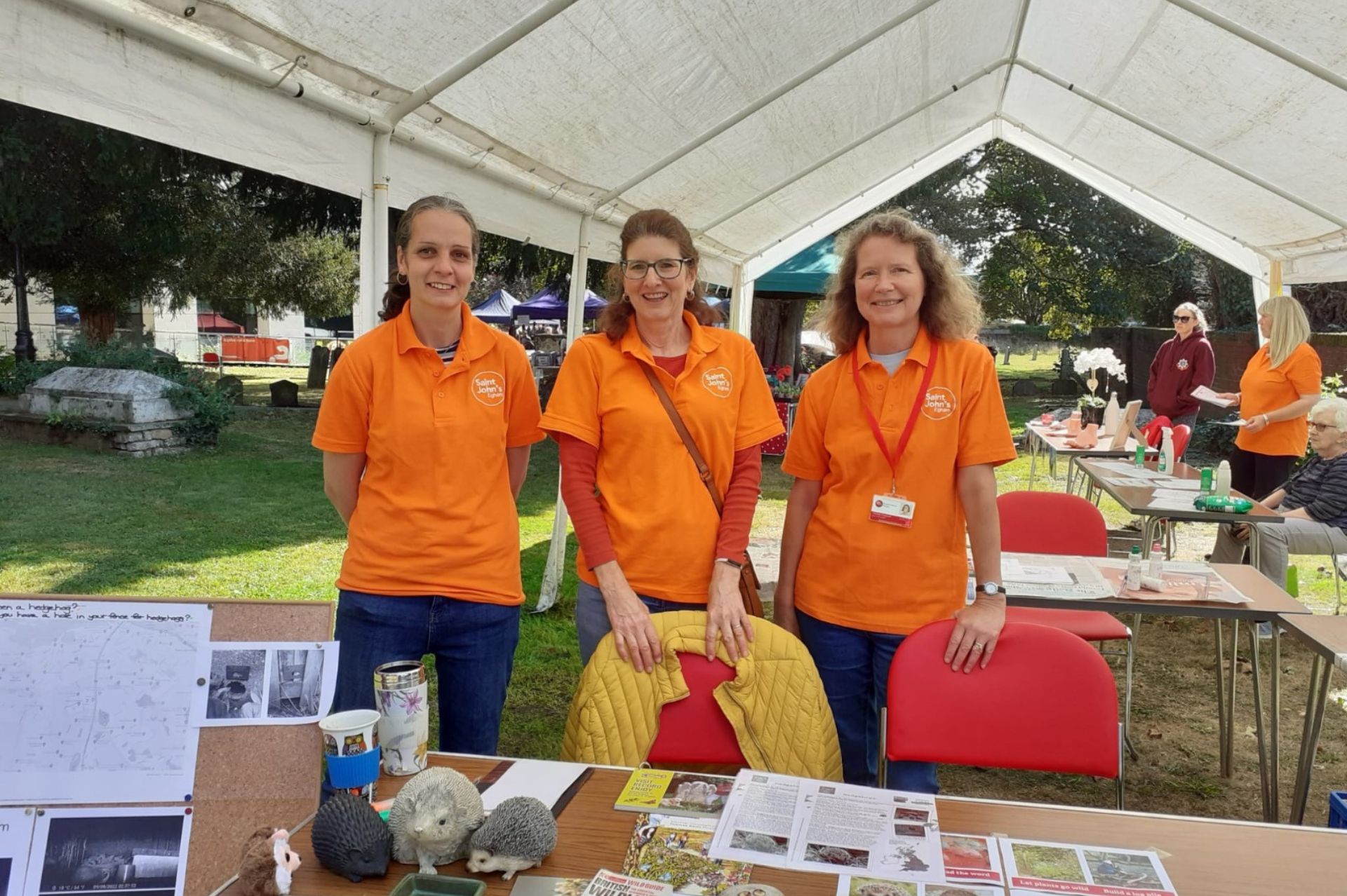 Three women wearing orange St John's t-shirts manning a wildlife stall