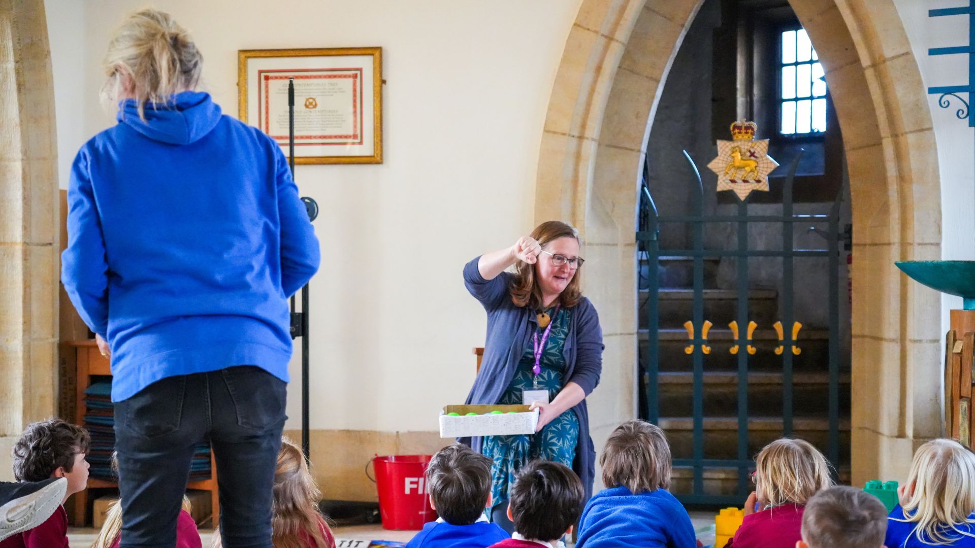 Volunteer and teacher in a church leading an activity in with school children in a church