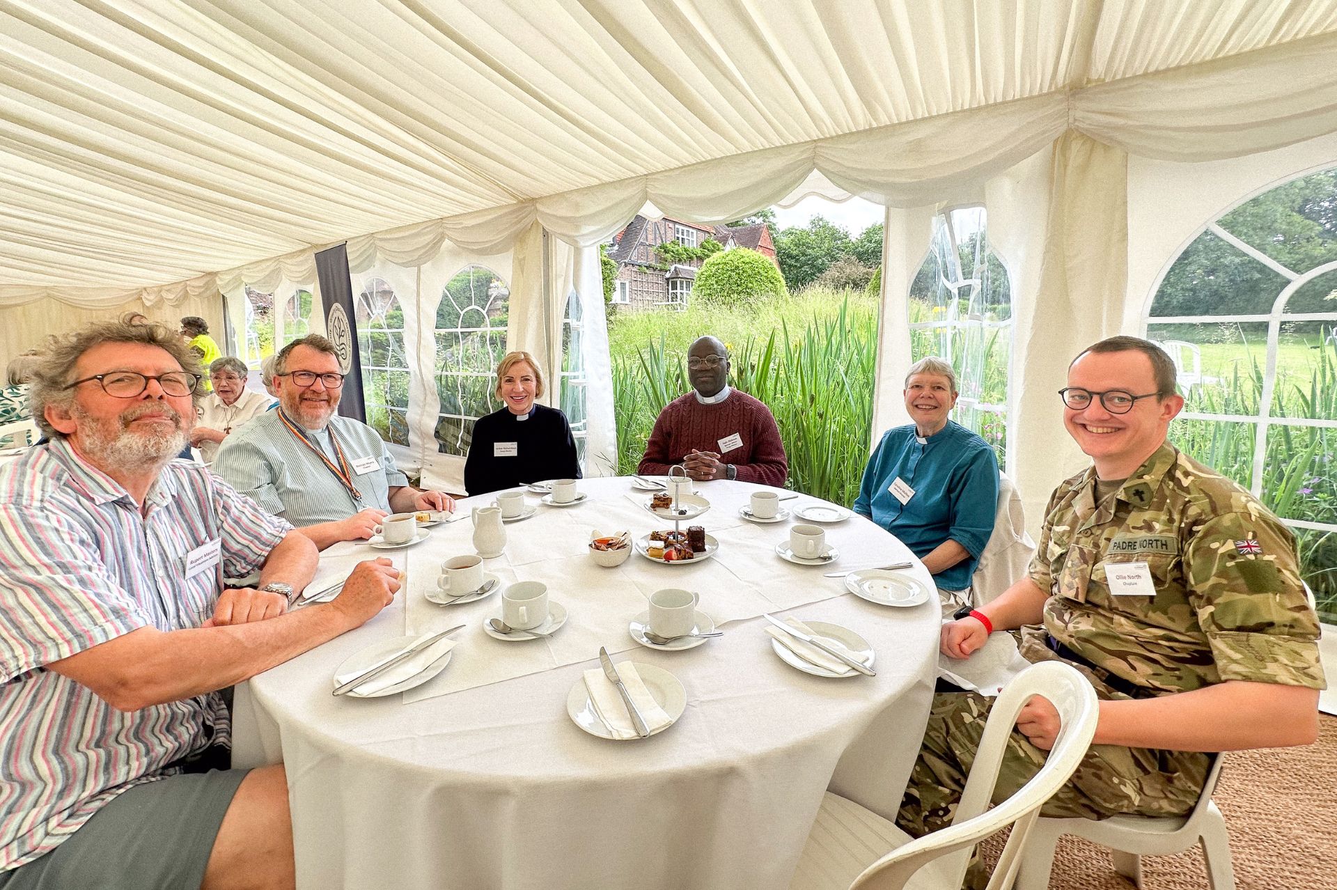 Attendees at the Listening Well Tent Week event pose for a photo sat around their table