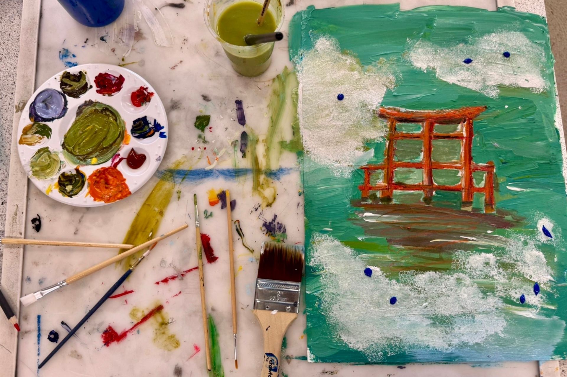 Image of a painting of an archway done by a young person, with paintbrushes, water pots and paint palette to the left of the painting