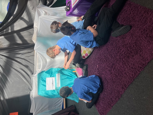 Four school boys sat interacting with activities in a prayer space in the school chapel