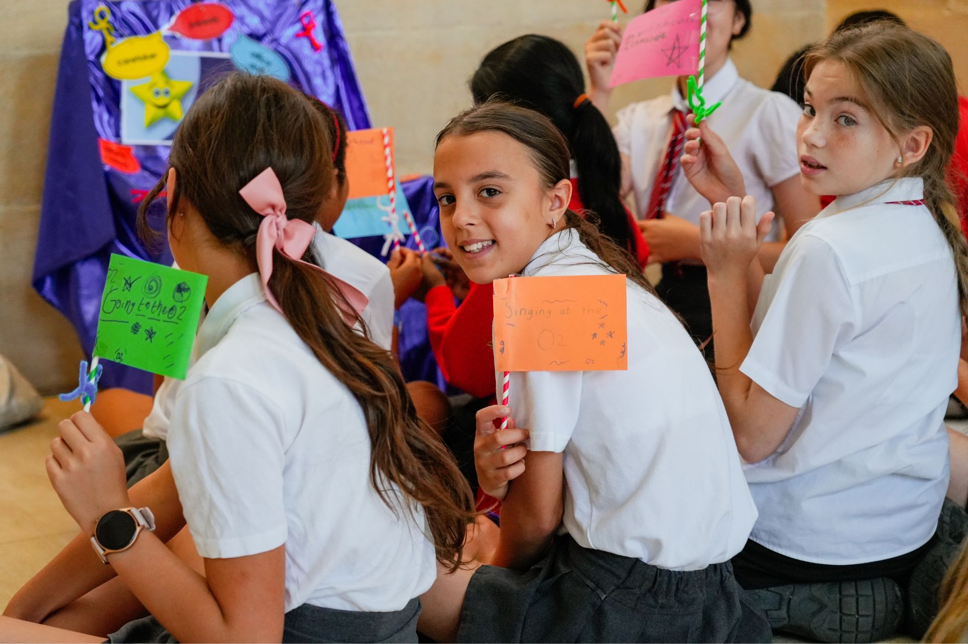 Girls in white school shirt with red ties holding crafted paper flags