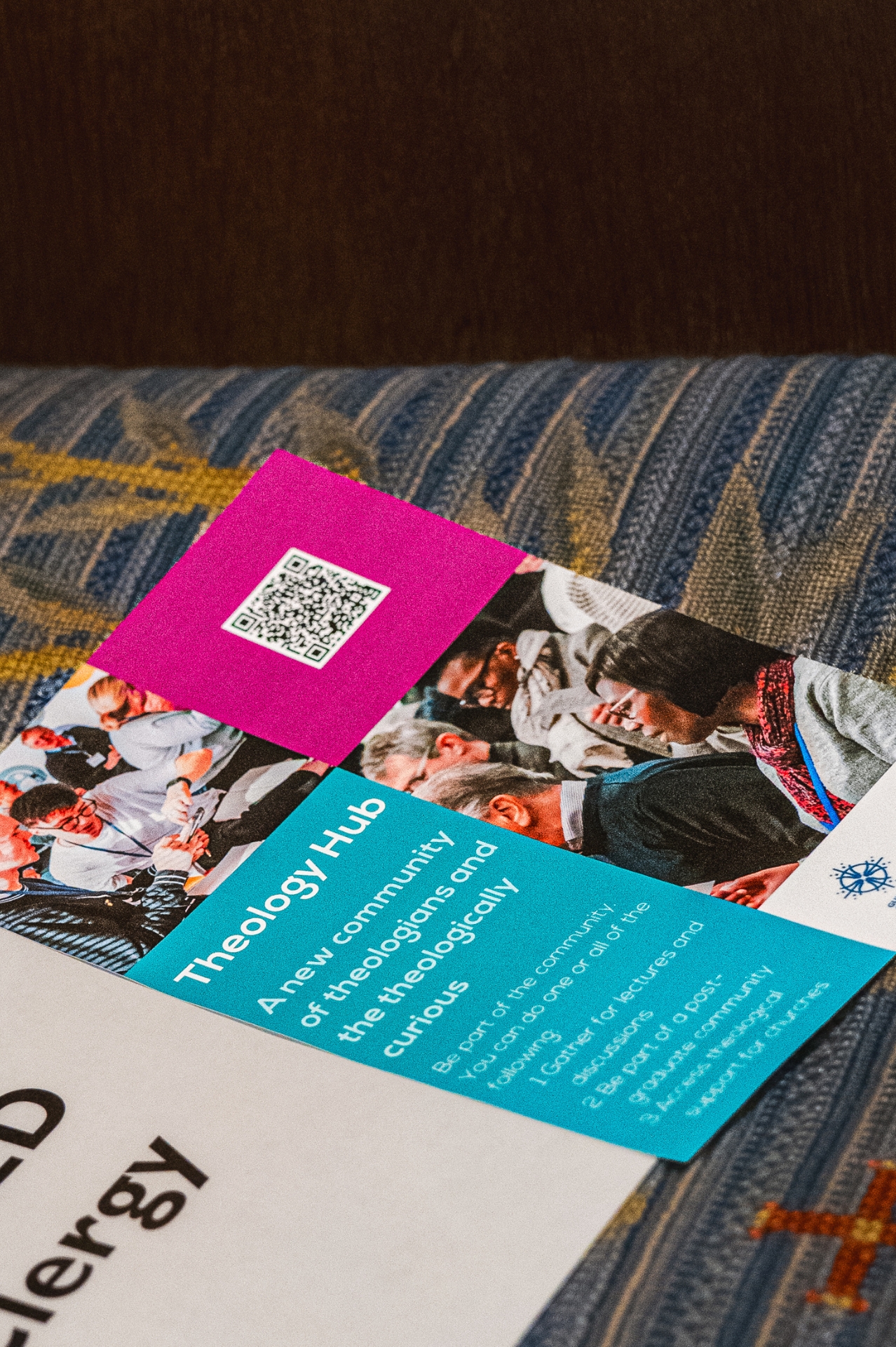 A leaflet with images and blue and purple coloured blocks laid on a chair entitled Theology Hub