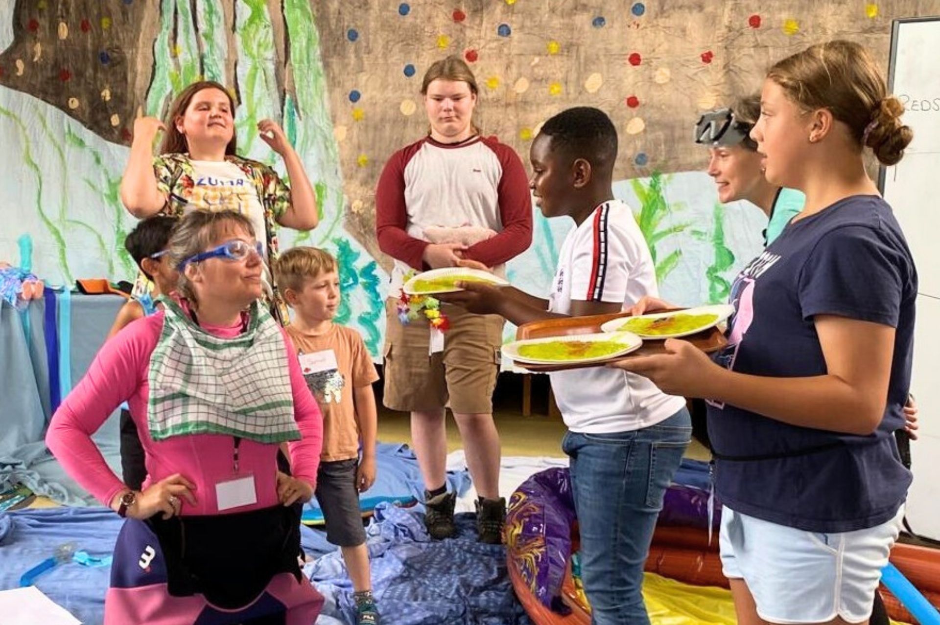 Children prepare to 'slime' a group leader dressed in a wetsuit and goggles